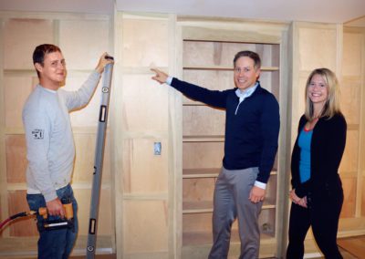 carpenter with happy homeowners in unfinished basement