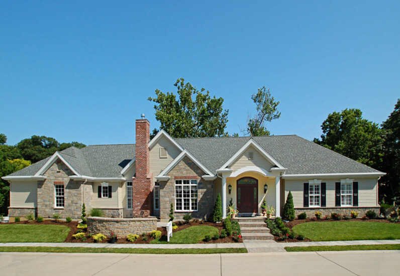 A new home build as seen from the street, showcasing rock and brickwork. By Agape Construction.