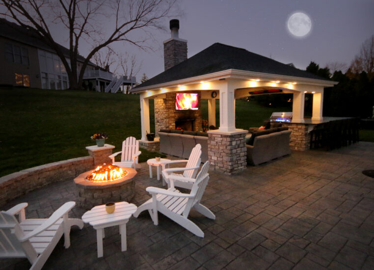A homeowner's private outdoor space with covered seating, TV, and fire pit by Agape Construction.