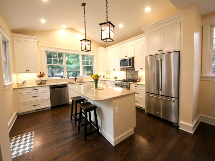 A home's kitchen and dining addition featuring a clean palette and spacious island by Agape Construction.