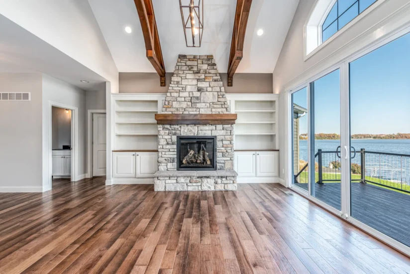 A lake home living area with fireplace, shelving, and access to outdoor decking. By Agape Construction.