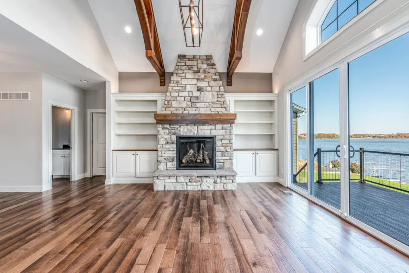 A lake home living area with fireplace, shelving, and access to outdoor decking. By Agape Construction.