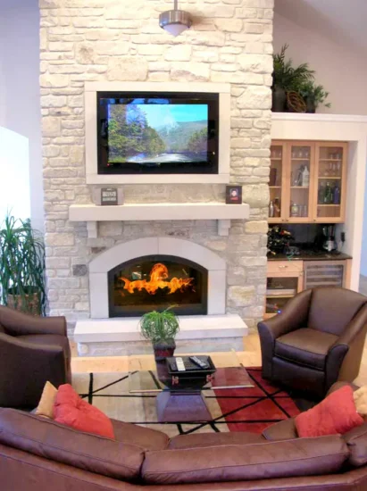 A light, natural stone fireplace with a tv on the hearth, by Agape Construction.