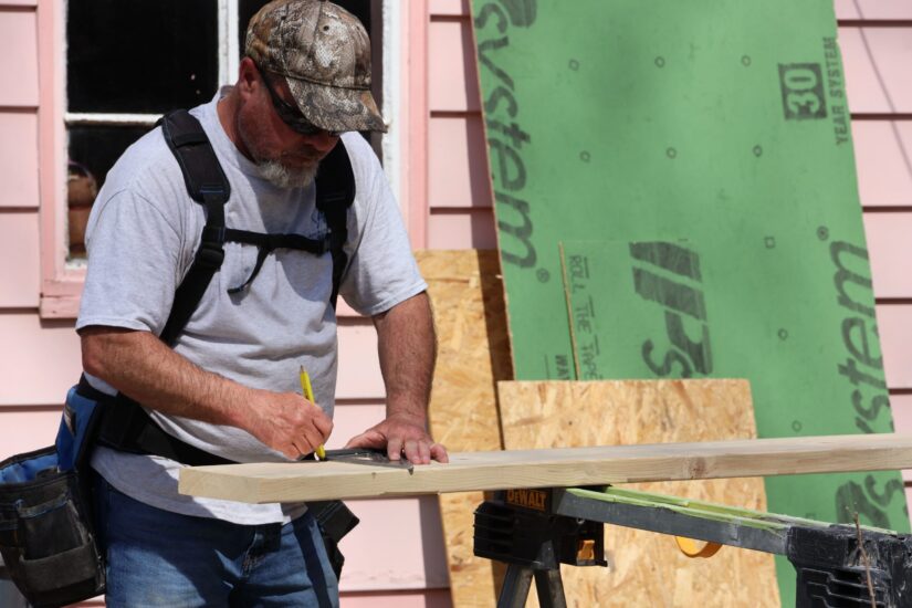 construction worker measuring wood for framing