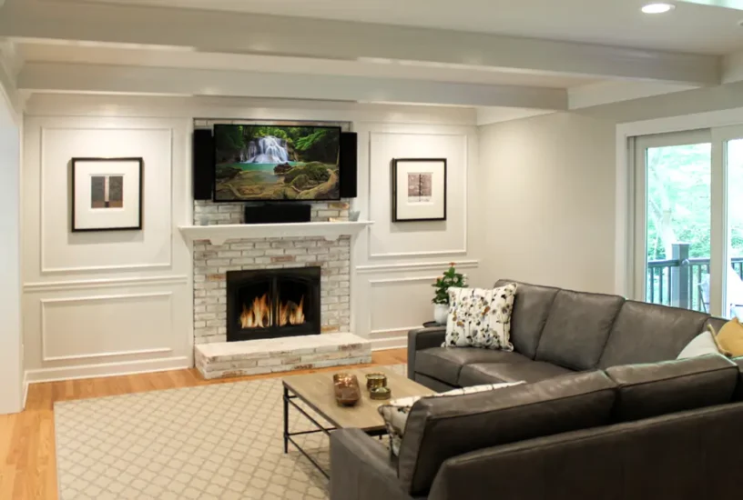 A home living area with stone fireplace, accent walls, and mounted tv. By Agape Construction.