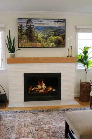 Modern, white brick fireplace with light stained-wood accents in a home living space. By Agape Construction.