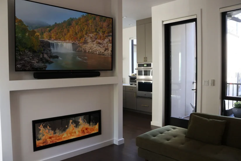A modern fireplace fixture that uses both sides of a wall for visibility in the kitchen and living room, by Agape Construction.