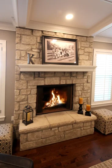 A homeowner's fireplace post-renovation, featuring stone accents and recessed lighting. By Agape Construction.